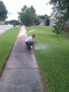 a Rancho Cordova Irrigatin Repair Tech adjusts a sprinkler line
